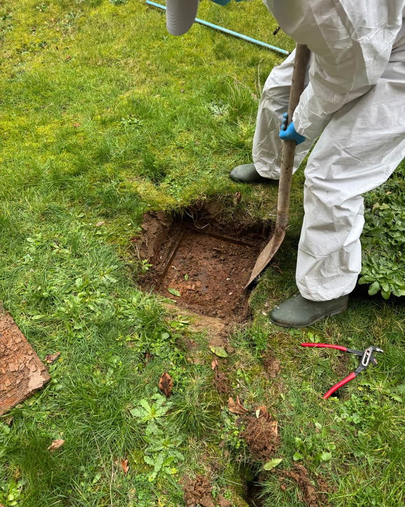 Opening a buried inspection chamber in a garden.